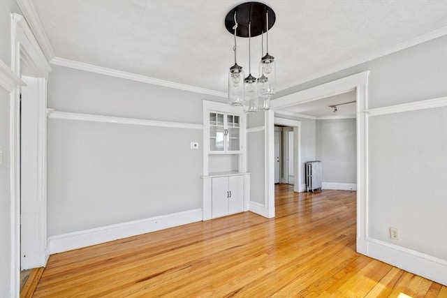 unfurnished dining area with baseboards, a chandelier, radiator heating unit, ornamental molding, and light wood-style flooring