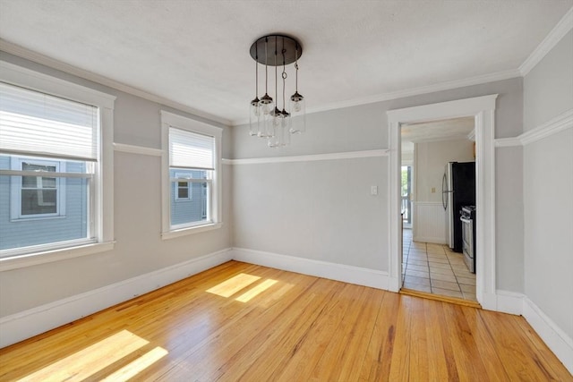 unfurnished room with crown molding, baseboards, plenty of natural light, and wood finished floors