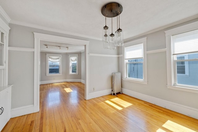 unfurnished dining area with baseboards, a chandelier, radiator, ornamental molding, and light wood-style flooring