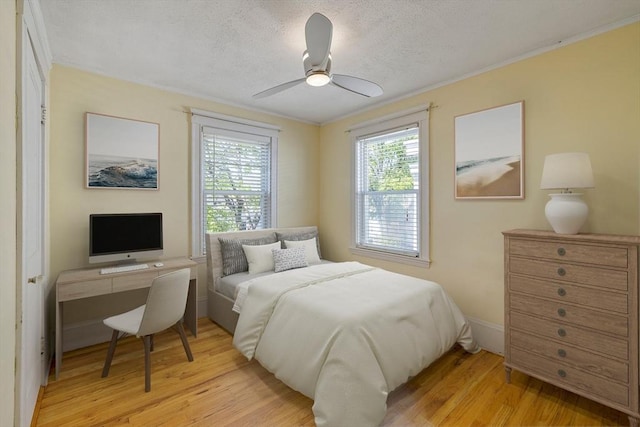 bedroom featuring light wood-style floors, a ceiling fan, a textured ceiling, and baseboards