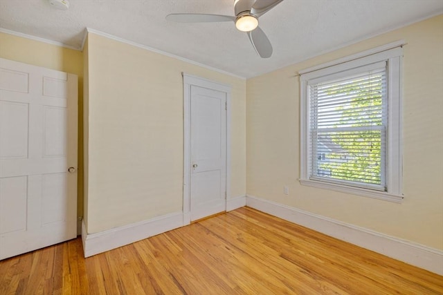 unfurnished bedroom with light wood-style floors, baseboards, crown molding, and ceiling fan