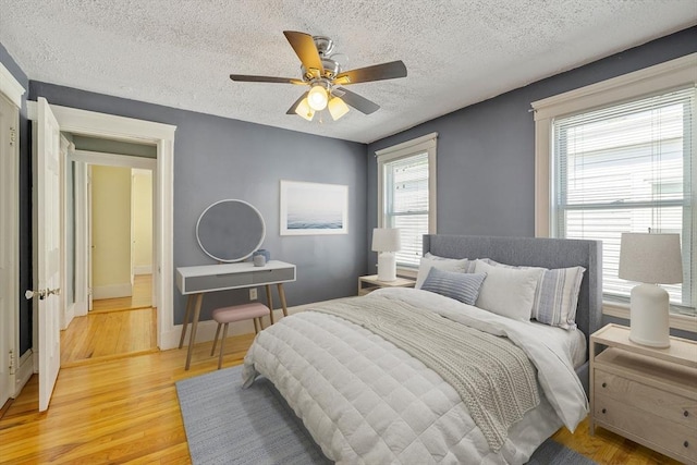 bedroom with a ceiling fan, a textured ceiling, and light wood finished floors