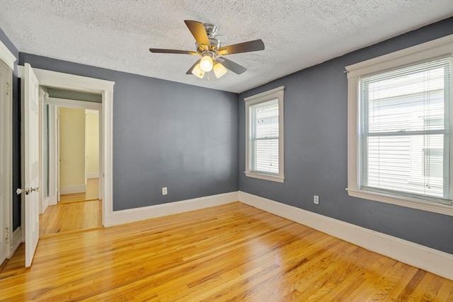 unfurnished room with baseboards, a textured ceiling, ceiling fan, and light wood-style flooring