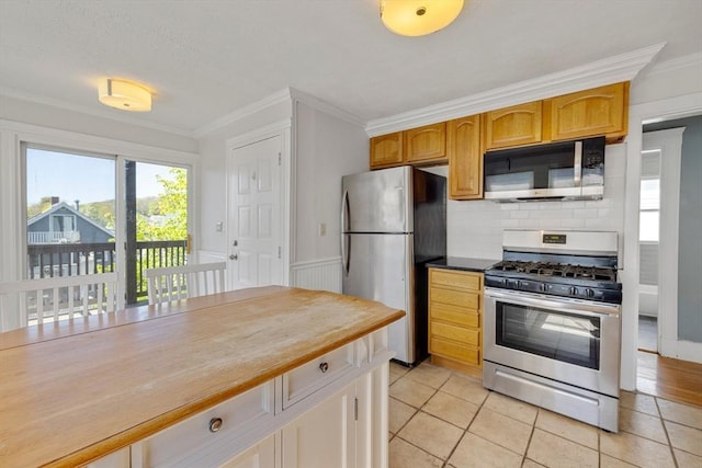 kitchen with crown molding, appliances with stainless steel finishes, decorative backsplash, and light tile patterned floors