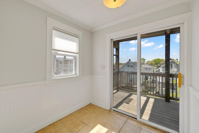 doorway featuring crown molding, light tile patterned floors, and wainscoting
