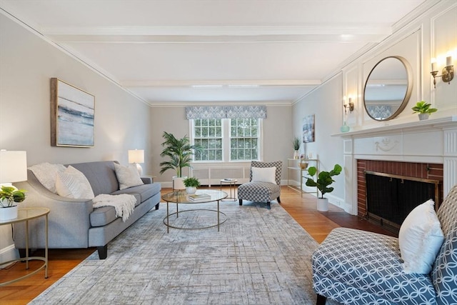 living room featuring beam ceiling, wood finished floors, a fireplace, crown molding, and baseboards