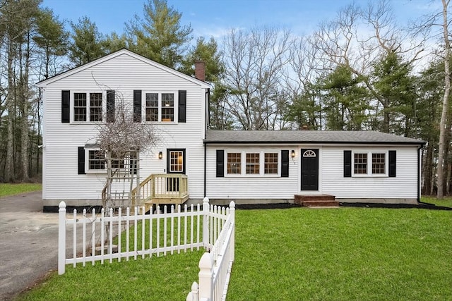 view of front of house featuring a chimney, fence, and a front lawn