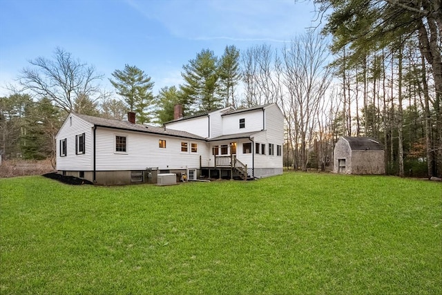 back of house featuring a chimney, an outdoor structure, a yard, and a shed