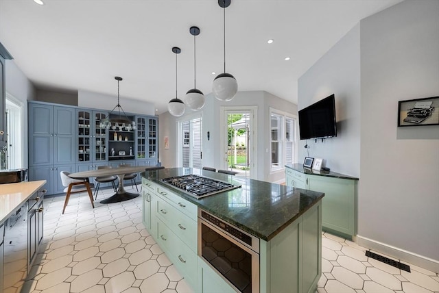 kitchen featuring stainless steel gas cooktop, recessed lighting, green cabinets, decorative light fixtures, and a center island