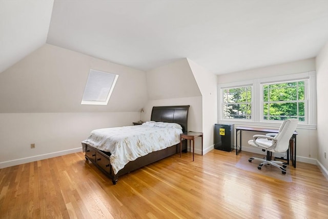 bedroom with lofted ceiling, light wood finished floors, baseboards, and a skylight