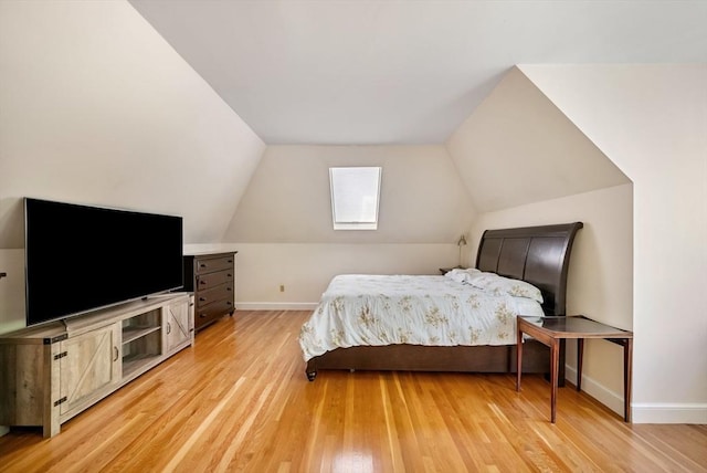 bedroom featuring light wood-style flooring, baseboards, and vaulted ceiling