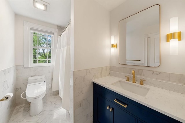 bathroom featuring tile walls, toilet, wainscoting, vanity, and marble finish flooring