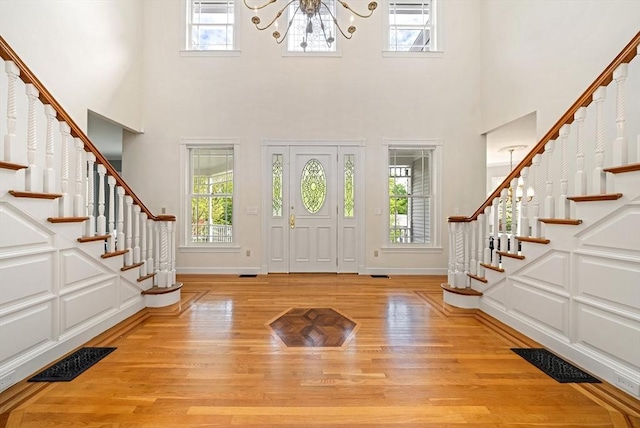 entryway featuring a chandelier, stairs, light wood-style floors, a high ceiling, and baseboards