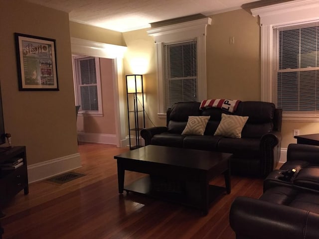 living room featuring ornamental molding, baseboards, and wood finished floors