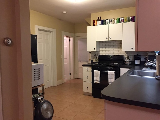 kitchen featuring black range with gas cooktop, a sink, white cabinetry, tasteful backsplash, and dark countertops