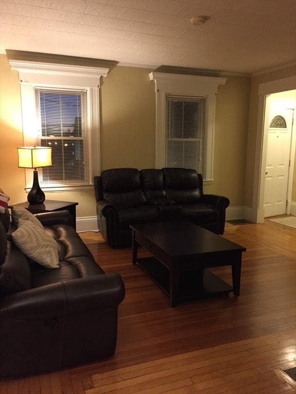 living area featuring crown molding, baseboards, and hardwood / wood-style flooring