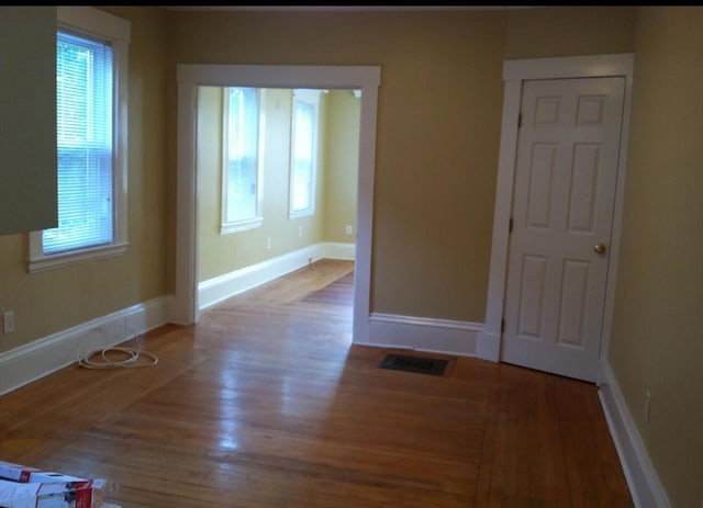 empty room with visible vents, baseboards, and wood finished floors