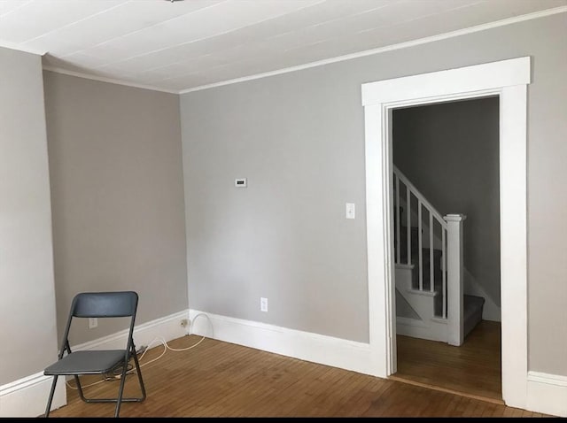 spare room featuring crown molding, stairs, baseboards, and wood finished floors