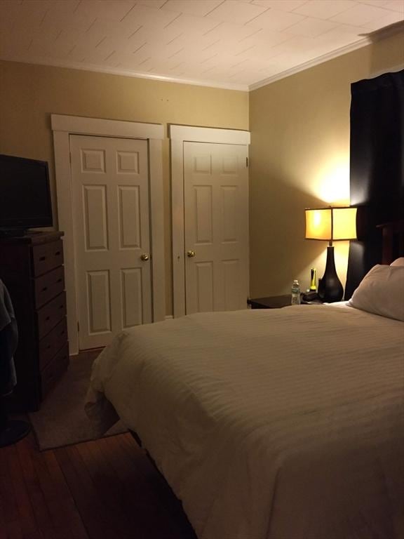 bedroom with ornamental molding and wood finished floors