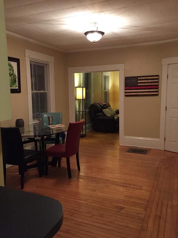 dining space featuring ornamental molding, baseboards, and wood finished floors