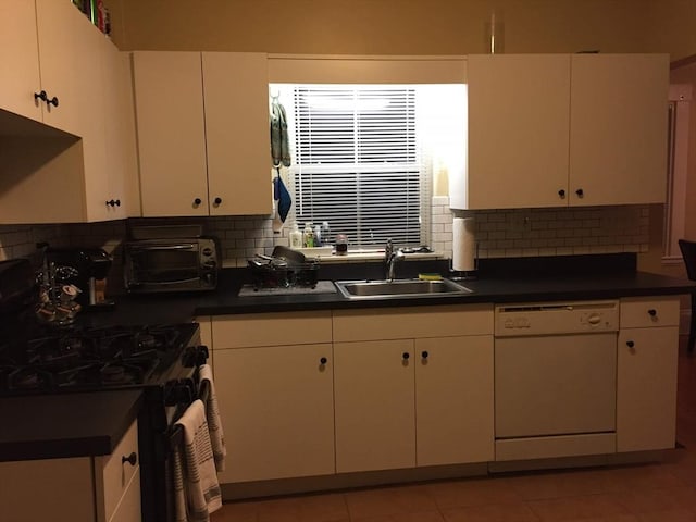 kitchen featuring decorative backsplash, black gas range oven, dark countertops, white dishwasher, and a sink