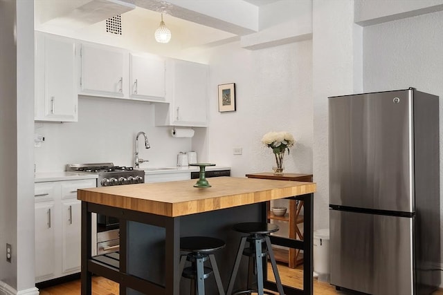 250 Beacon Unit 1B, Boston, MA 02116 - kitchen with appliances with stainless steel finishes, a sink, butcher block counters, white cabinetry, and a textured wall
