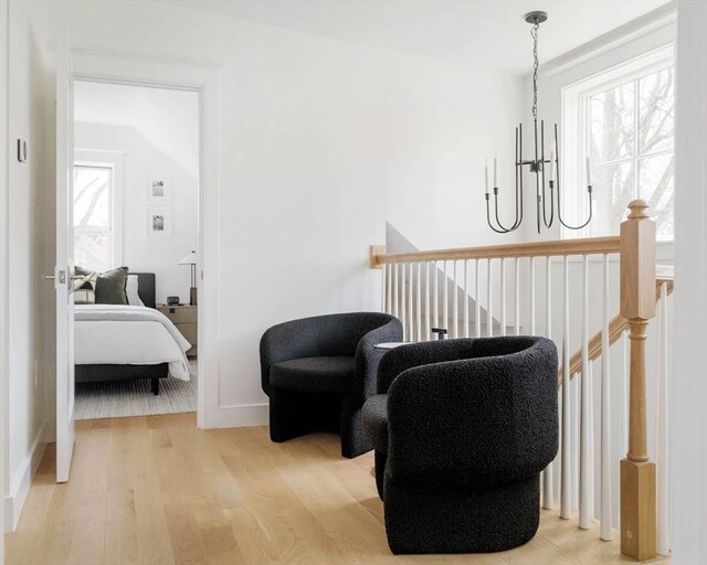 living area featuring baseboards, a notable chandelier, wood finished floors, and an upstairs landing
