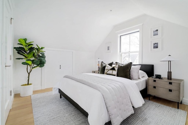 bedroom with vaulted ceiling and light wood-type flooring
