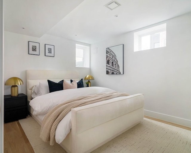 bedroom with visible vents, light wood finished floors, baseboards, and multiple windows