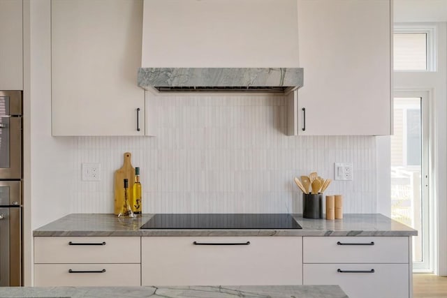 kitchen with wall chimney range hood, white cabinetry, decorative backsplash, and black electric cooktop