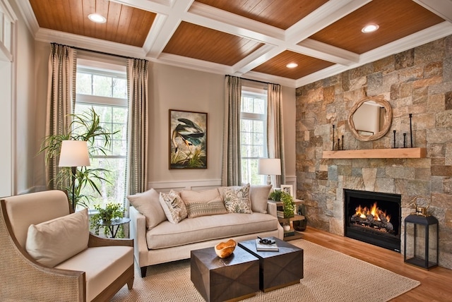 living room featuring coffered ceiling, a stone fireplace, beam ceiling, wood ceiling, and wood-type flooring