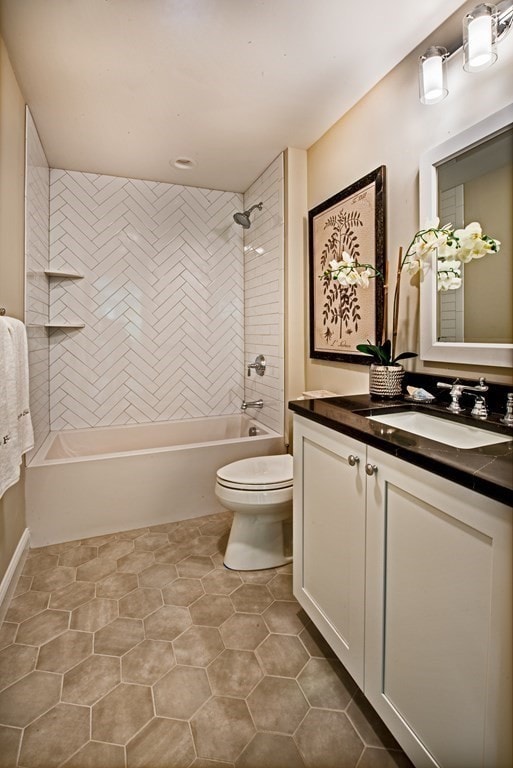 full bathroom featuring tiled shower / bath, vanity, toilet, and tile flooring