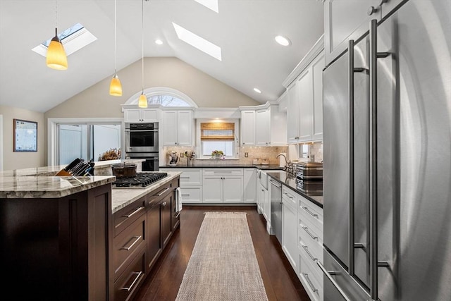 kitchen featuring dark stone countertops, white cabinetry, dark hardwood / wood-style floors, decorative light fixtures, and stainless steel appliances