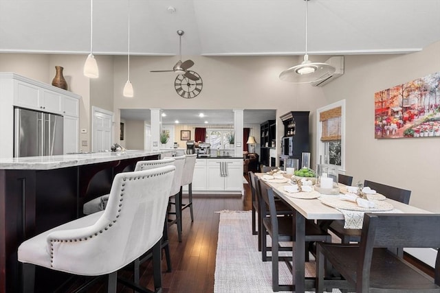 dining area featuring a wall unit AC, ceiling fan, dark hardwood / wood-style flooring, ornate columns, and a high ceiling