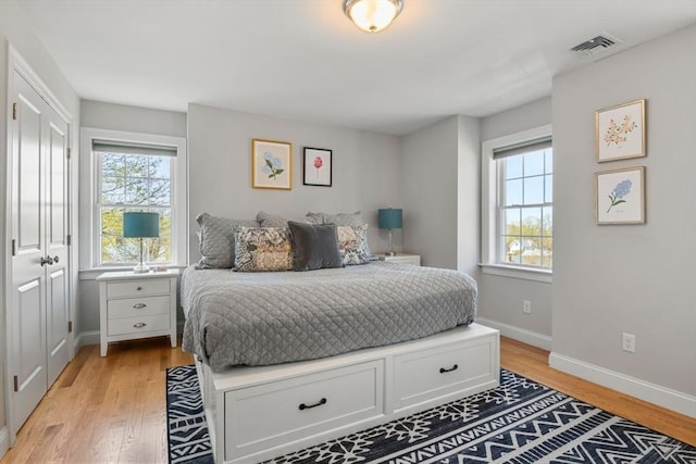 bedroom with multiple windows, light wood finished floors, and visible vents