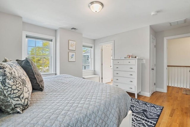bedroom with light wood-style floors, baseboards, and visible vents