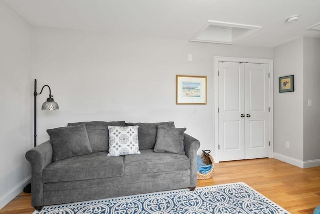 living area with baseboards, wood finished floors, and attic access