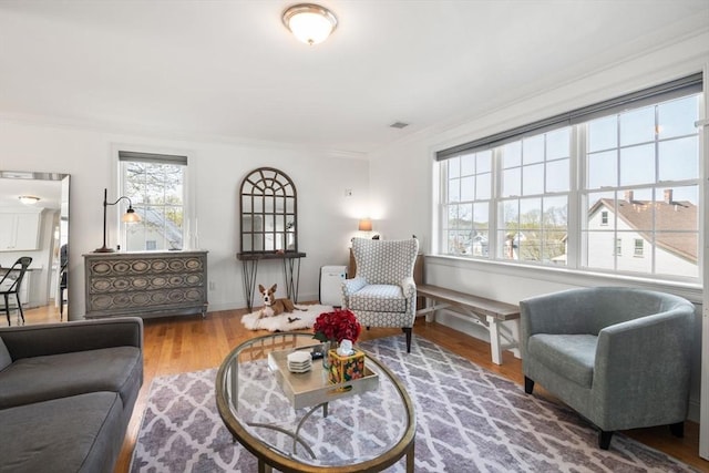 living area featuring crown molding, baseboards, and wood finished floors