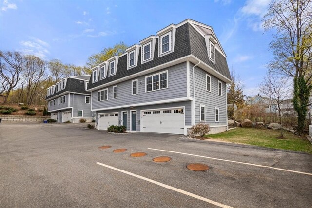 view of front of property with mansard roof, a shingled roof, and an attached garage