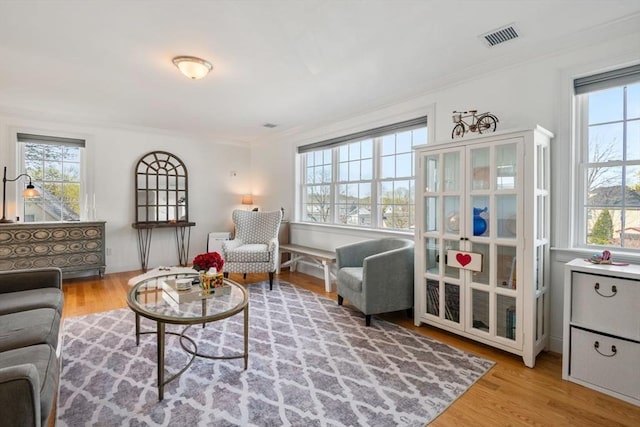 interior space featuring visible vents, ornamental molding, and wood finished floors