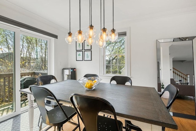 dining area with a healthy amount of sunlight, ornamental molding, stairs, and wood finished floors