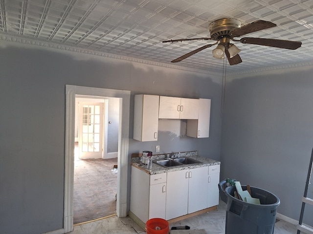 kitchen with ceiling fan, sink, white cabinets, and light stone counters