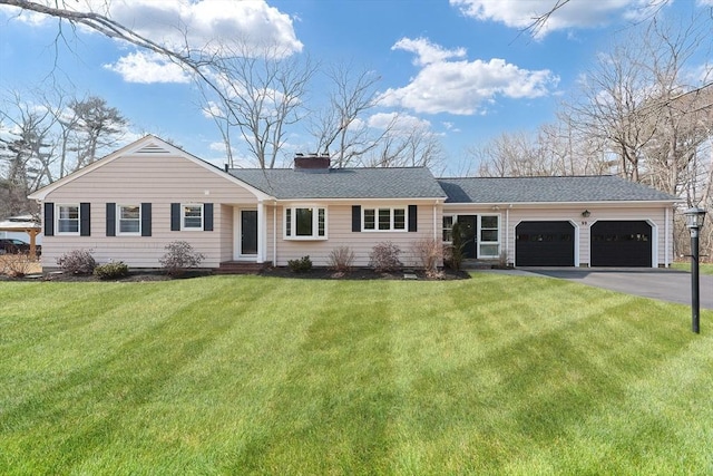 single story home with an attached garage, a shingled roof, driveway, a front lawn, and a chimney