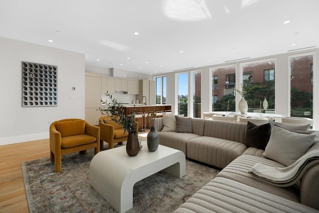 living area with light wood-type flooring, baseboards, and recessed lighting