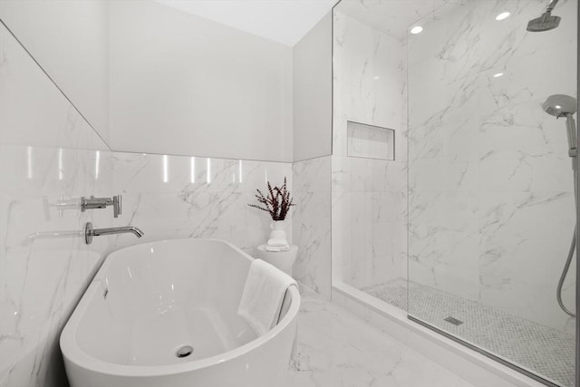 full bathroom with marble finish floor, a freestanding tub, and a marble finish shower