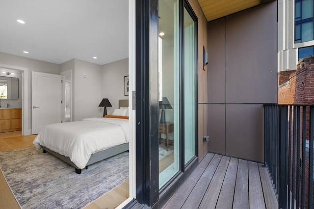 bedroom featuring ensuite bath, wood finished floors, and recessed lighting