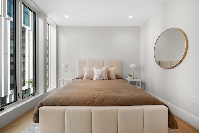 bedroom with expansive windows, recessed lighting, wood finished floors, and baseboards