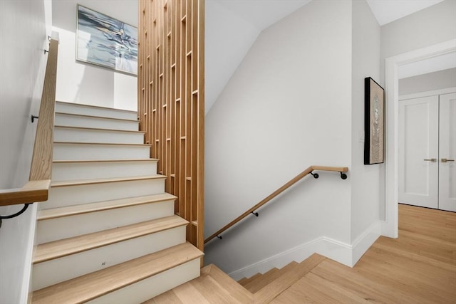 staircase featuring vaulted ceiling, baseboards, and wood finished floors