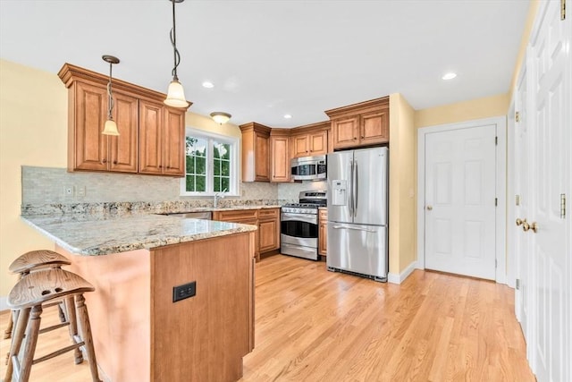 80 Schooner Ln, Barnstable, MA 02601 - kitchen with appliances with stainless steel finishes, a peninsula, brown cabinetry, light wood-type flooring, and tasteful backsplash