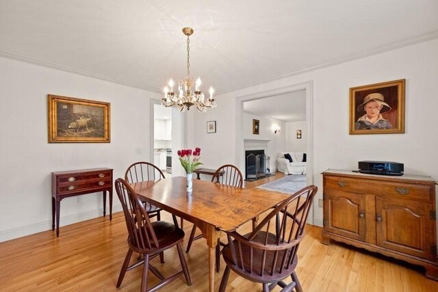 307 Riverview Dr, Chatham, MA 02633 - dining room featuring a fireplace, light wood-style floors, baseboards, and a notable chandelier